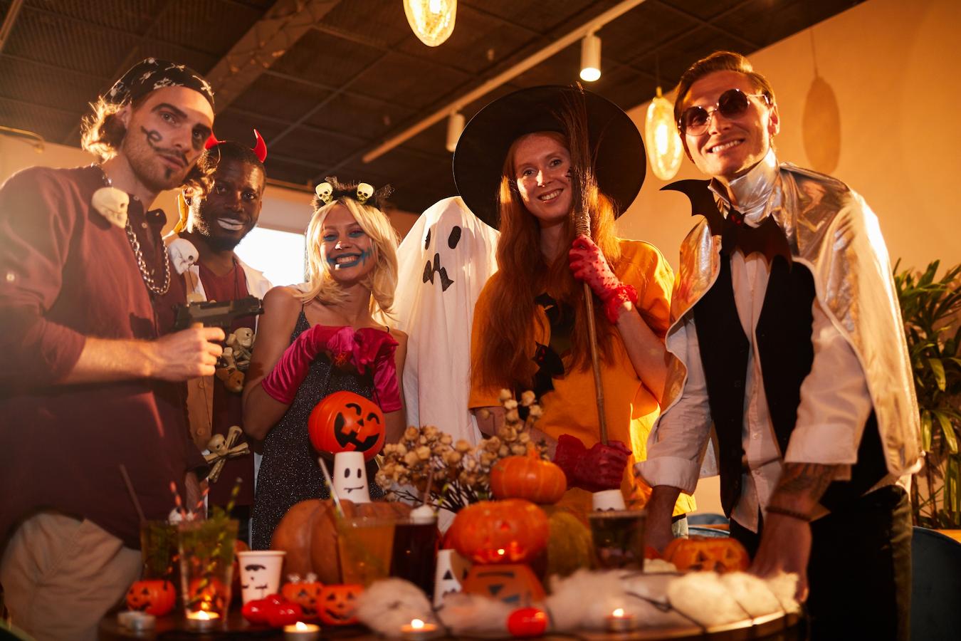 a group of people in Halloween costumes posing in a festive area decorating decorate party theme costumes ideas