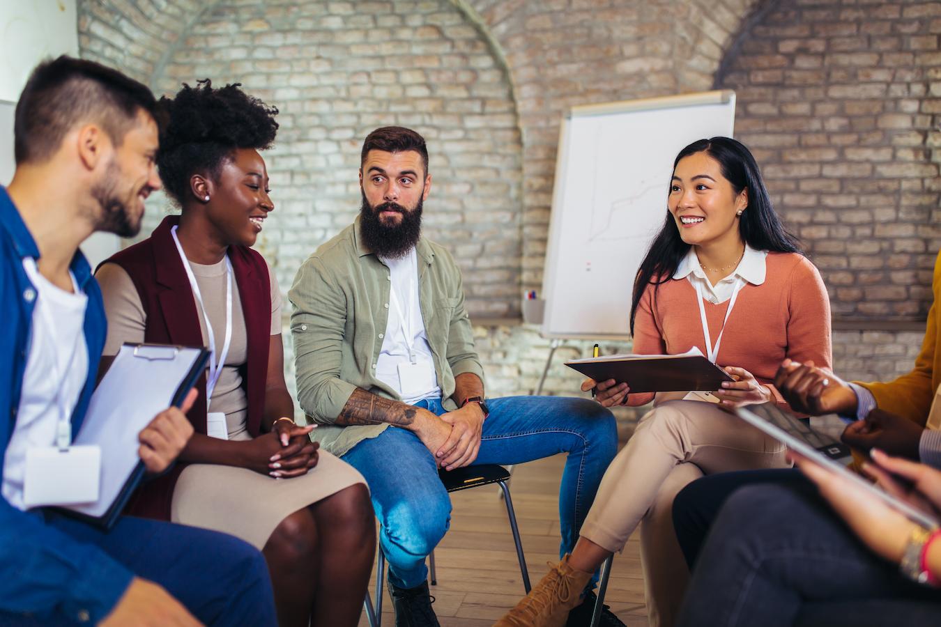 Colleagues sit in a circle at the office for a team exercise