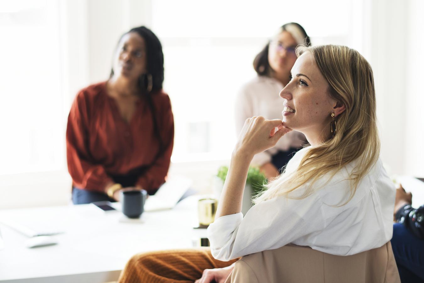 Employees sit at table and listen to presentation
