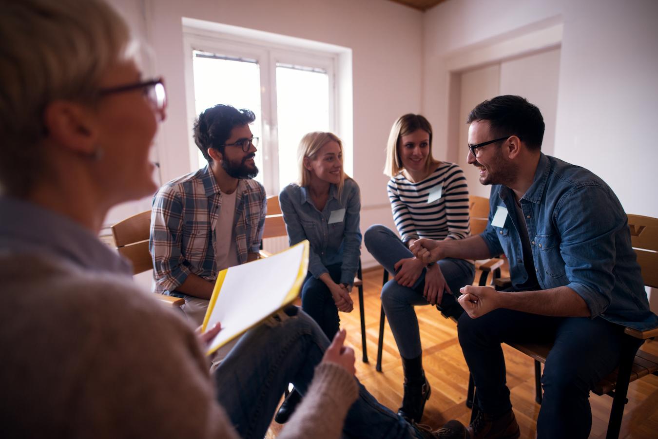 Five people laugh and talk in office