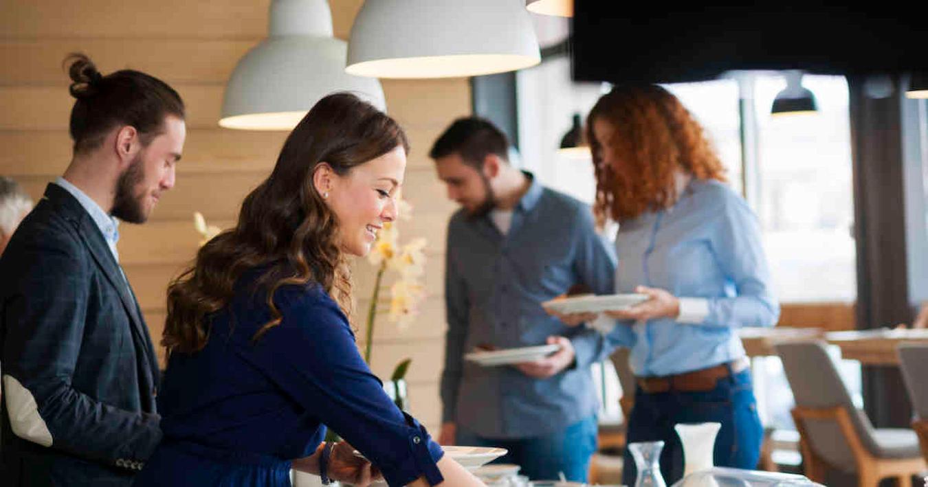 girl getting food at a company buffet new city team laughing corporate event retreat agenda happy hour new skills new ideas nearby park in person