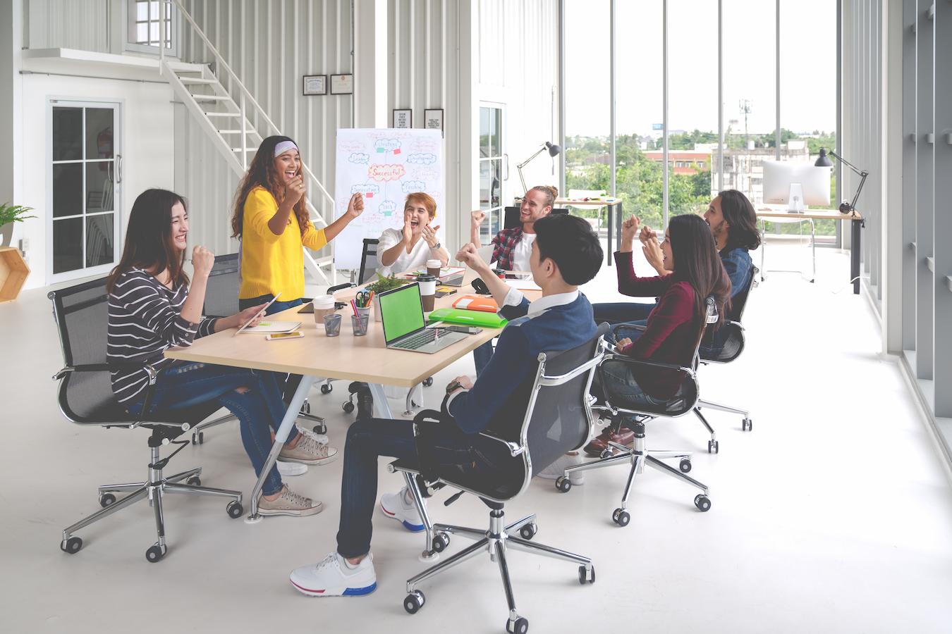 Group of colleagues around conference table smile as they create a workplace success plan for their organization