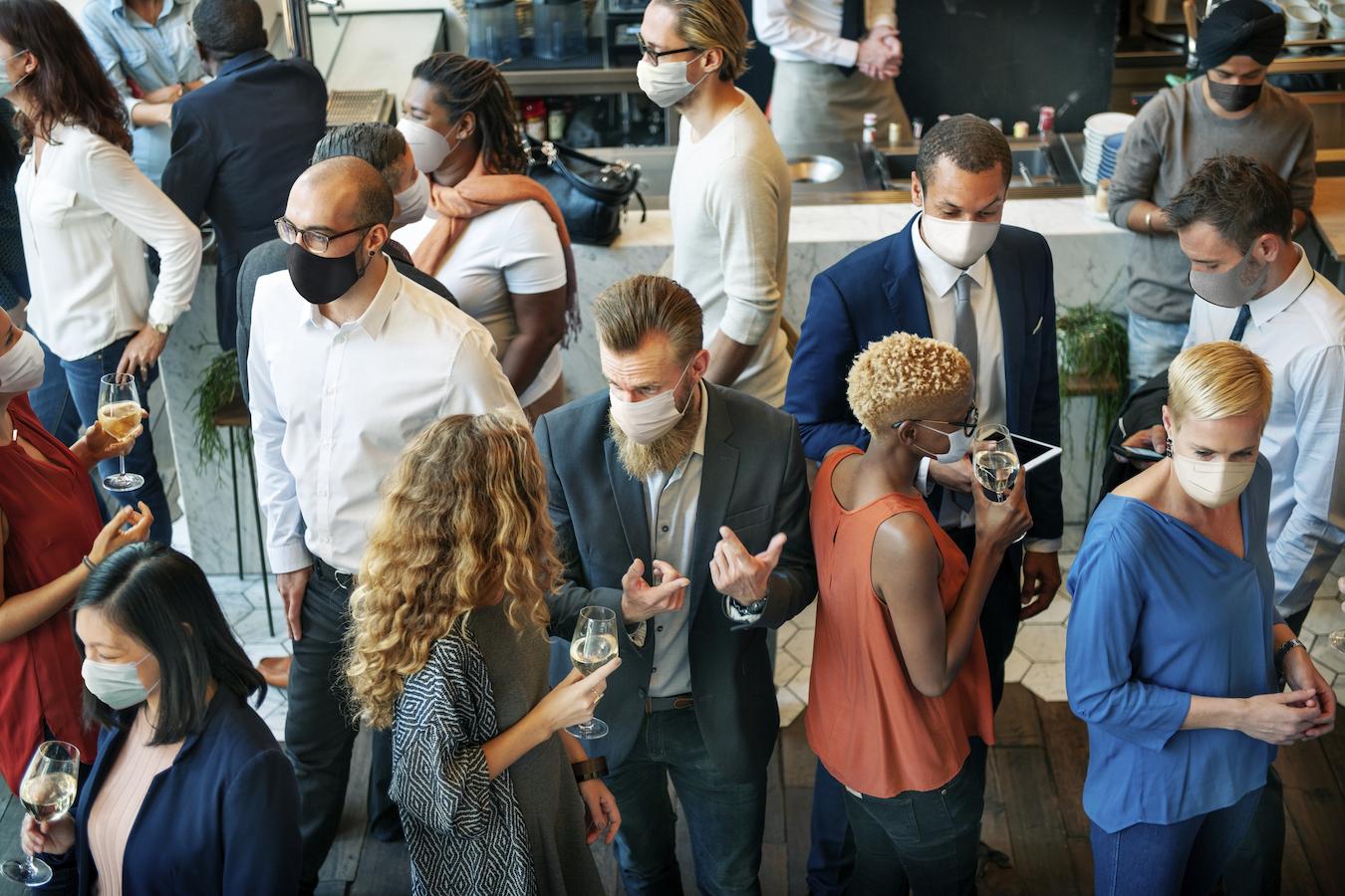Masked individuals mingle at an event