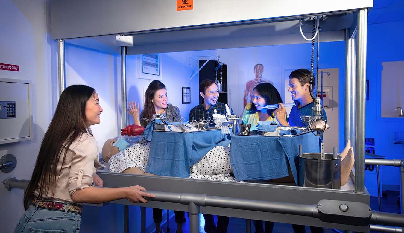 people playing a game with a patient dummy company retreat ideas team building retreats conference room cooking class free time boost company morale