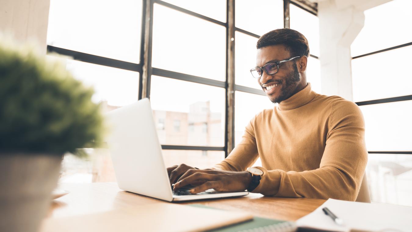 Productive workplace employee sits at desk and types a business plan for next quarter at their company