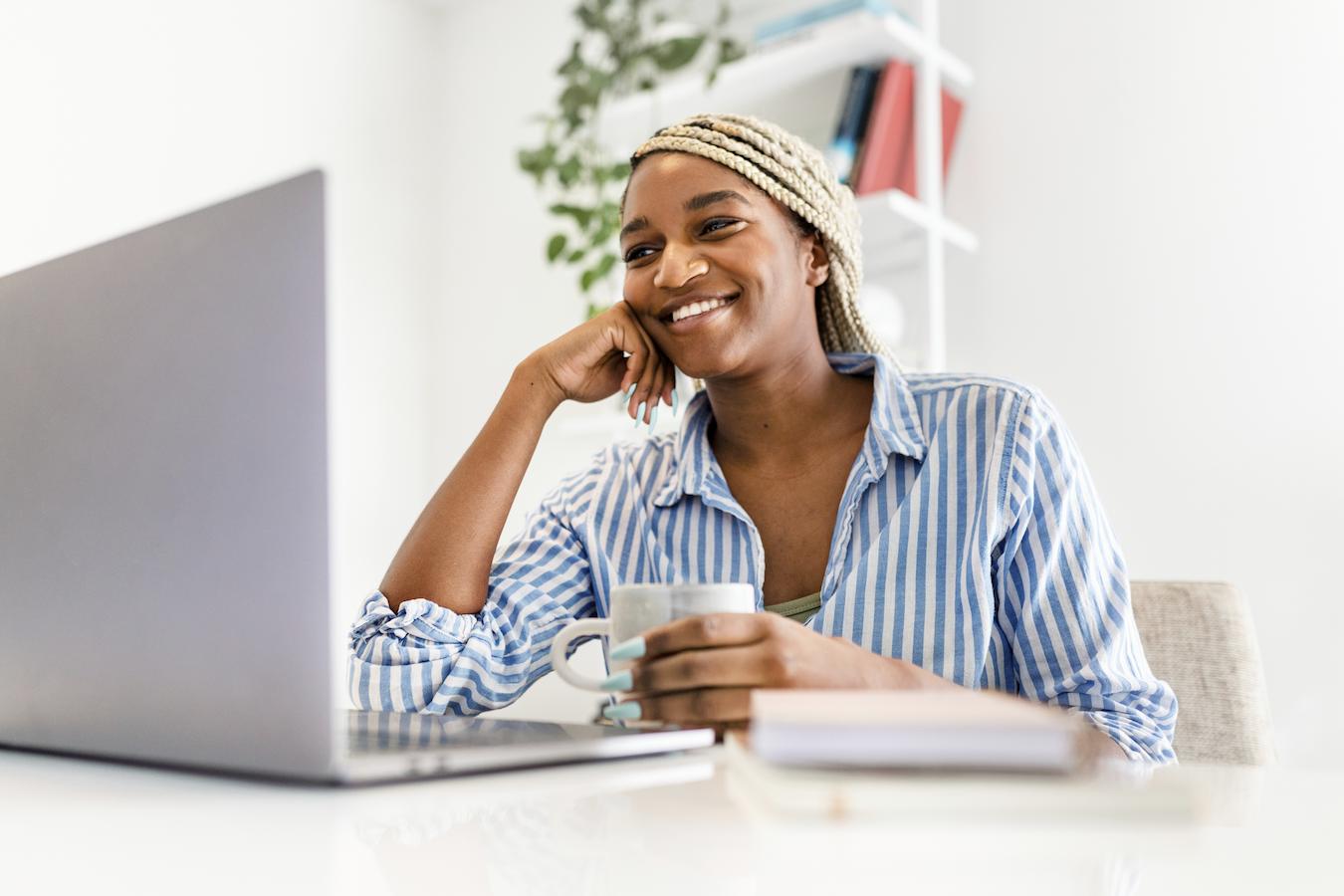 Remote employee in blue striped button down smiles while sitting at computer