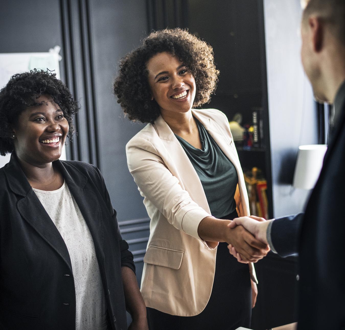 Three people smile at each other and two shake hands