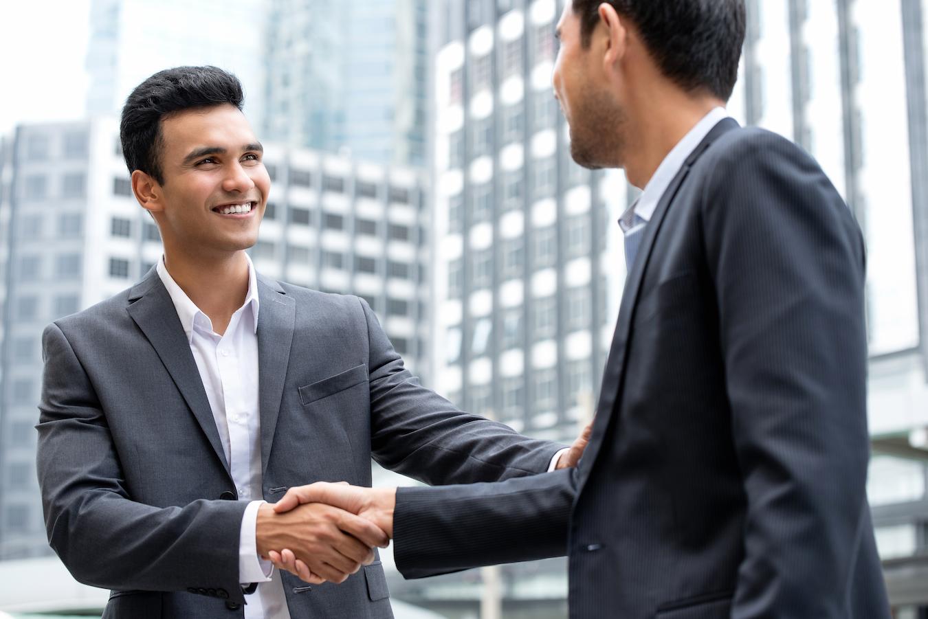 Two colleagues in business suits are building rapport as they shake hands and develop a stronger relationship