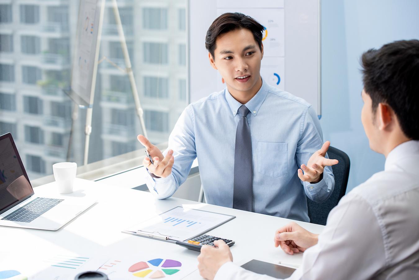 Two colleagues in city office sit at desk and discuss event sponsorship