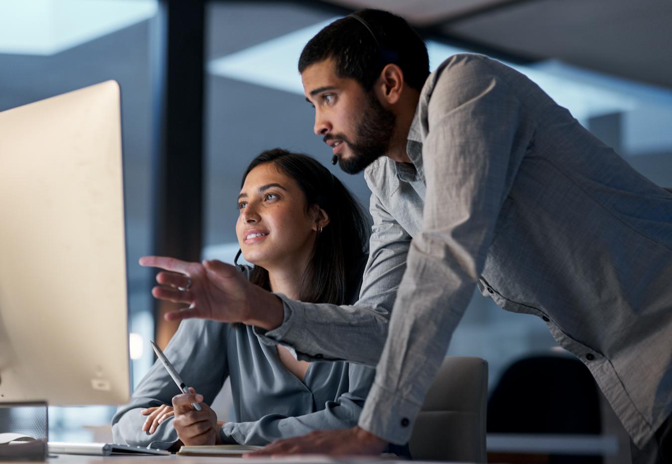 Two colleagues in front of a computer demonstrate how to build rapport by practicing good communication and sharing business ideas