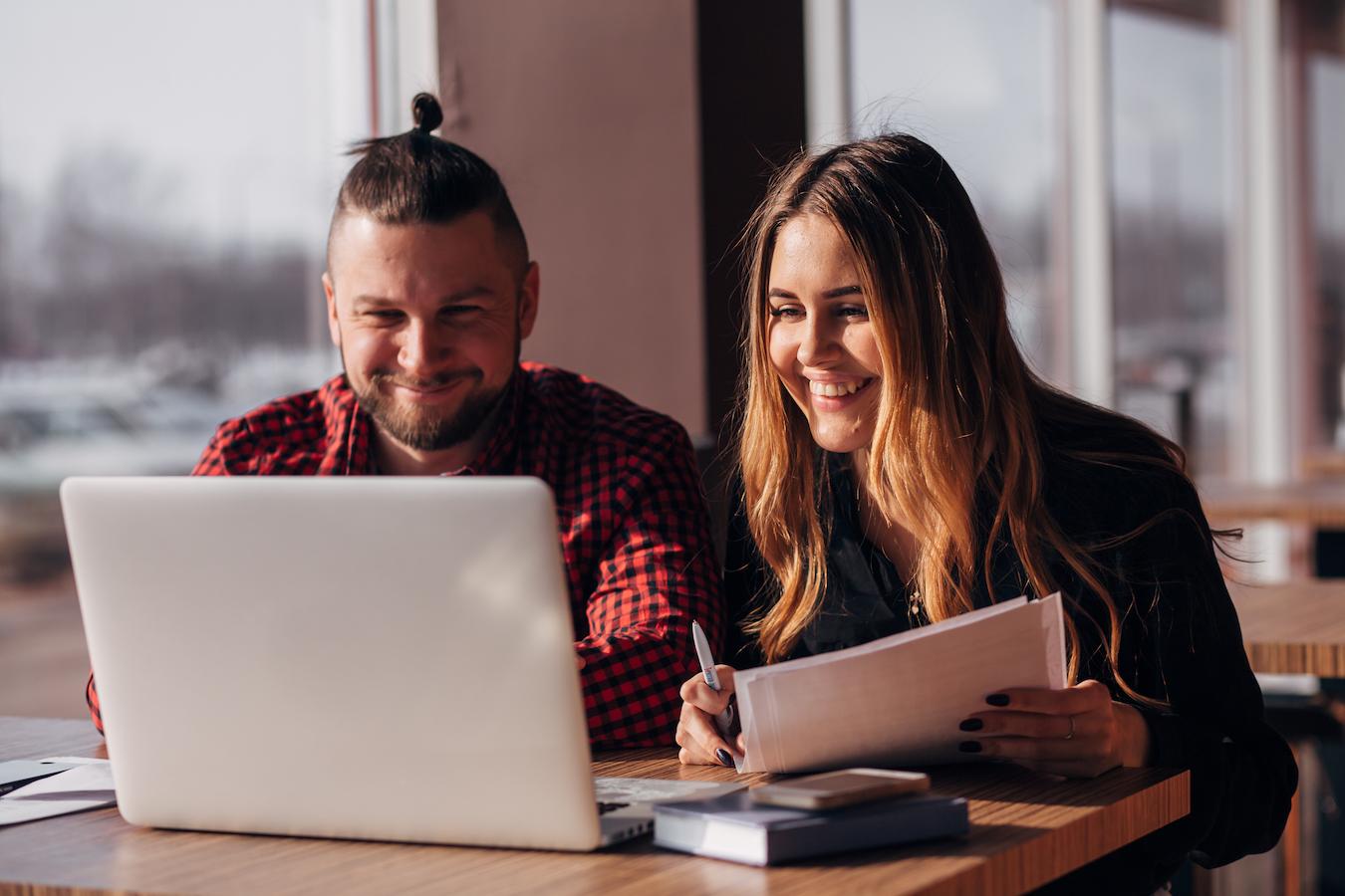 Two event planners talk to event sponsor over video chat in sunny office