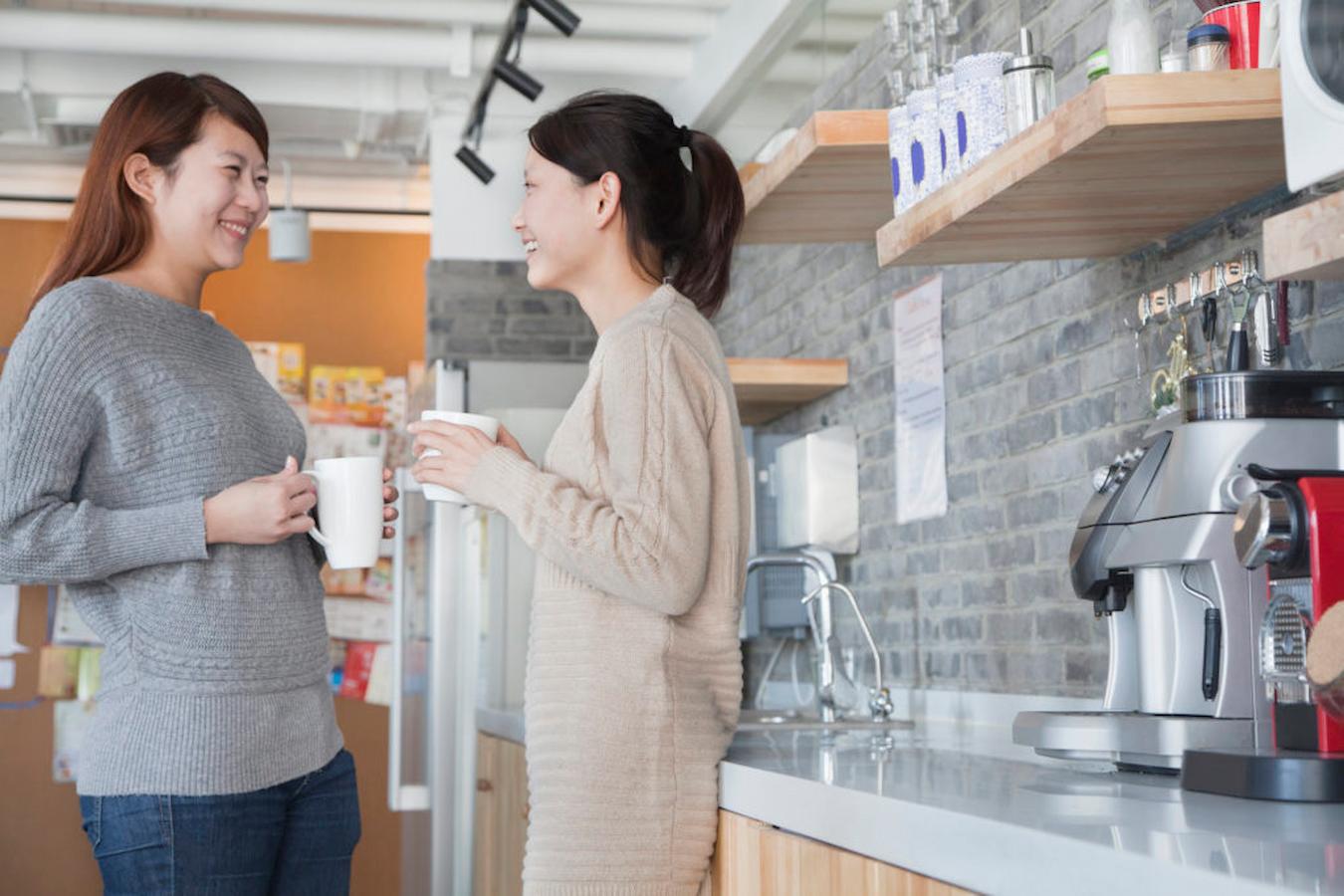 two women talking at a workplace coffee station fun team building activities bonding power fall themed team building new season beer tasting work week happy hour pumpkin spice hybrid team feel fast paced